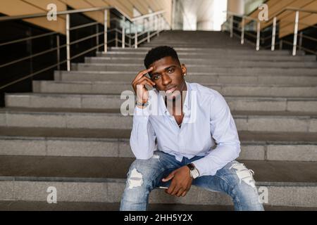 Thoughtful young man sitting on steps Stock Photo