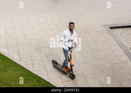 Young man with electric push scooter on footpath Stock Photo
