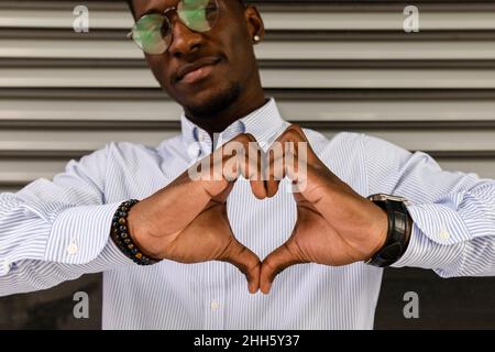Young man making heart shape with hands Stock Photo