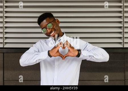 Smiling man making heart shape with hands Stock Photo