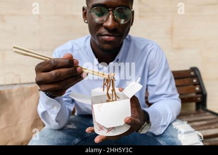 Man having noodles with chopsticks Stock Photo