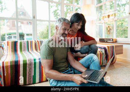 Smiling mature couple using laptop at home Stock Photo