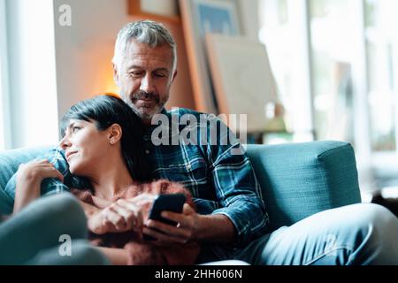 Man using smart phone with woman at home Stock Photo