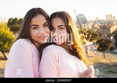 Young woman with smiling sister holding sparklers