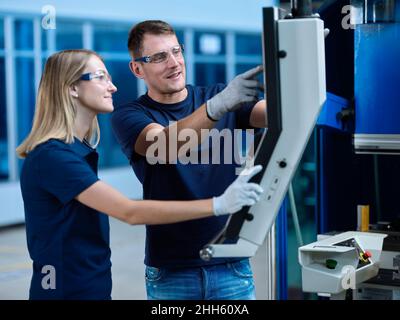 Technicians wearing protective eyewear discussing over CNC machine Stock Photo