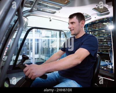 Blue-collar worker driving forklift in factory Stock Photo