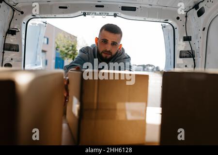 Young delivery person arranging boxes in van Stock Photo
