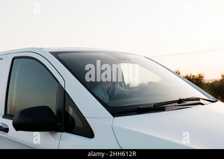 Delivery man in white van at sunset Stock Photo