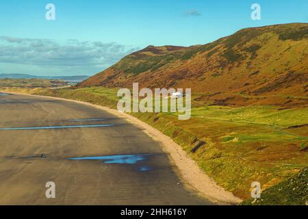 Rhossili Downs behind the old Vicarage and looking down over Rhossili Bay or Beach on the end of the Gower Peninsula Stock Photo
