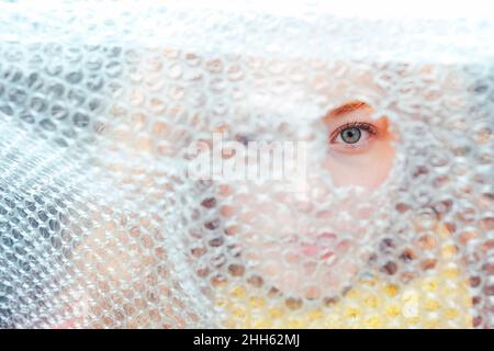 Woman looking through torn bubble wrap Stock Photo