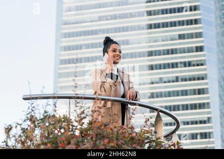 Smiling freelancer talking on mobile phone by railing Stock Photo