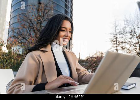 Smiling young freelancer using laptop working at table Stock Photo