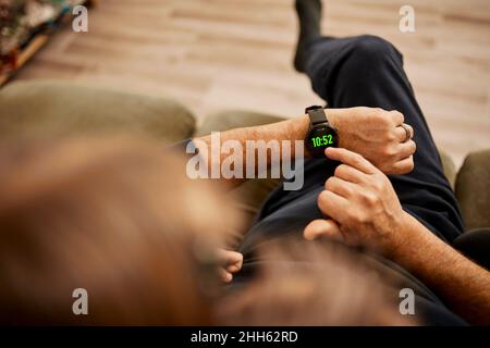 Grandfather using smart watch with granddaughter sitting at home Stock Photo