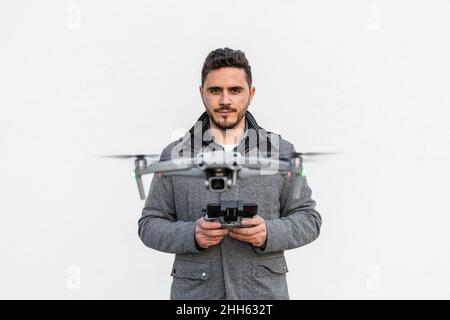 Confident man flying drone against white background Stock Photo