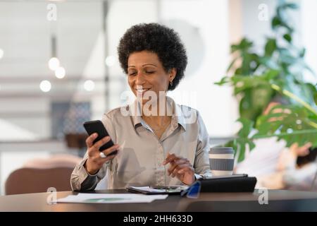 Smiling businesswoman using smart phone at office Stock Photo