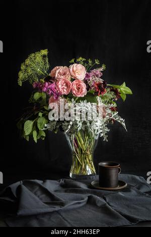 Studio shot of coffee cup and bouquet of Mini Eden roses, annual claries (Salvia viridis), Queen Annes lace (Daucus carota), black-eyed Susans (Rudbeckia hirta), silver ragwort (Jacobaea maritima), mint and dill Stock Photo