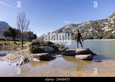 Hiker standing on rock and admiring mountains, Cuber Dam, Mallorca, Balearic Islands, Spain Stock Photo