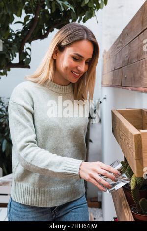 Woman watering cactus plant at home Stock Photo