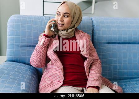 Pregnant woman talking on smart phone in living room Stock Photo