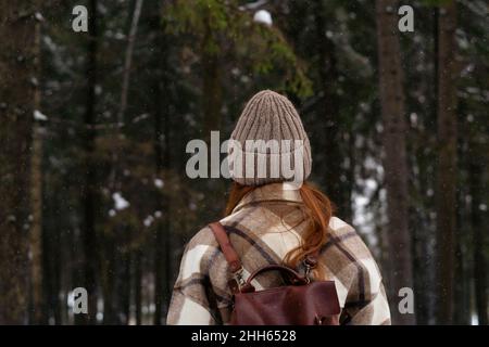 Woman wearing knit hat and backpack in forest Stock Photo