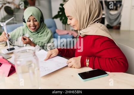 Happy colleagues discussing over document at home Stock Photo