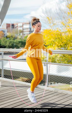 Determined young athlete exercising with jumping rope on bridge Stock Photo