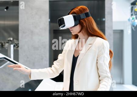 Businesswoman wearing virtual reality simulator and using touch screen device at workplace Stock Photo