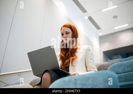 Confident working woman using laptop sitting in convention center Stock Photo