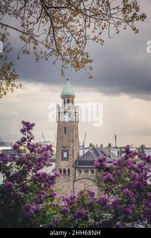 Germany, Hamburg, Clock tower in Saint Pauli Piers with blooming flowers in foreground Stock Photo