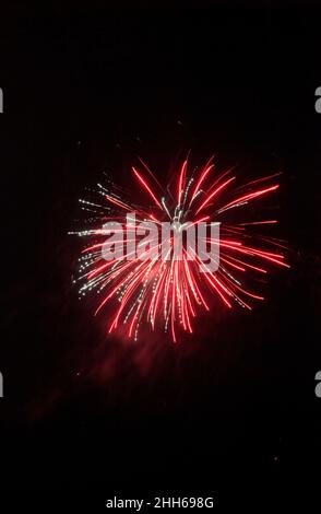 Red fireworks exploding against clear night sky Stock Photo