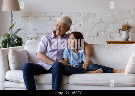 Happy dreamy grandfather and grandson kid sitting, relaxing on couch Stock Photo