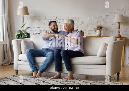 Excited senior father and adult grownup son giving fist bump Stock Photo