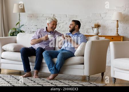 Cheerful grownup son and happy senior father enjoying coffee break Stock Photo