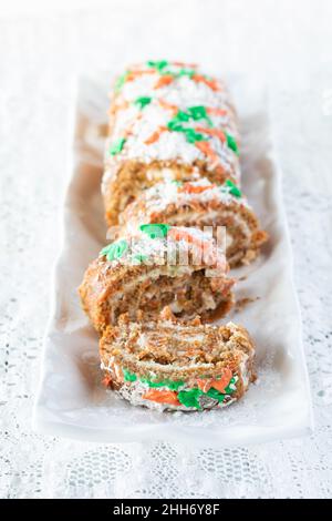 Carrot cake jelly roll cut into slices on a platter against a white background. Stock Photo