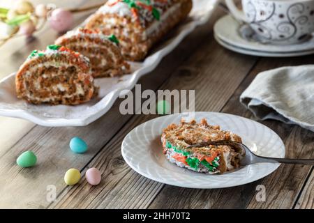 A serving of carrot cake jelly roll with a platter of the same in behind. Stock Photo