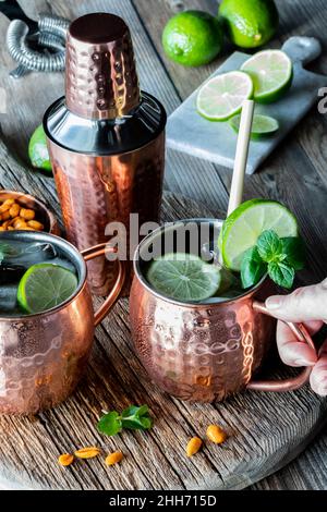 Hand holding an icy cold Moscow Mule with ginger beer cocktail. 