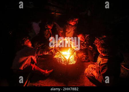 Gaza Strip, Palestine. 23rd January 2022. A Palestinian family sits around a fire to warm themselves inside their house during the cold weather at the Kha Yunis refugee camp in the southern Gaza Strip. Credit: Majority World CIC/Alamy Live News Stock Photo