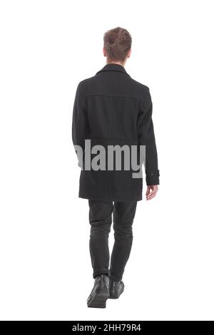 Back view of going handsome young business man in coat walking away. Isolated over white background. Stock Photo