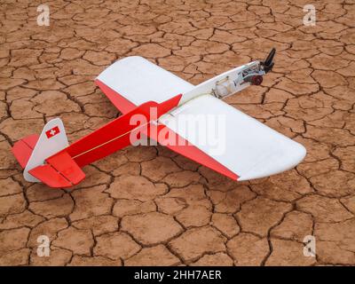 Model airplane on a desert floor in red Stock Photo