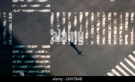 Elevated view over a man using smartphone on pedestrian crossing in road intersection of Japan. Aerial of person with phone device at crosswalk. Asia Stock Photo
