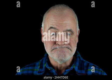 An elderly man looks down with a contrite face. Stock Photo