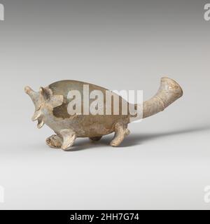 Glass bottle in the shape of an animal ca. 3rd century A.D. Roman Colorless with yellowish tinge; trail and applied feet in same glass.Thick rim, folded over and in, with flattened upper lip; tubular neck, turned upwards; elongated ovoid body; pontil pad on bottom between ears and mouth; four broad pads applied in pairs on underside of body, tooled and pinched to look like feet.Single trail wound once around neck; around bottom, side pinched out to form two ears and projecting mouth.Intact; many pinprick bubbles and blowing striations; dulling, pitting, thick creamy weathering, and iridescence Stock Photo