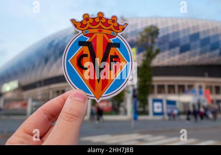 September 12, 2021, Villarreal, Spain. The emblem of the football club Villarreal CF against the background of a modern stadium. Stock Photo