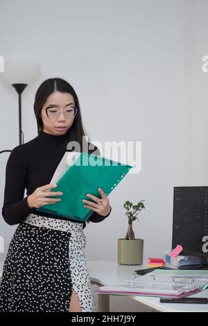 Serious asian business woman analyzing indexes and financial charts. Stock Photo
