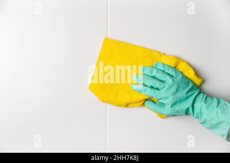 Close-up of a gloved hand holds a rag and washes ceramic tiles at home Stock Photo