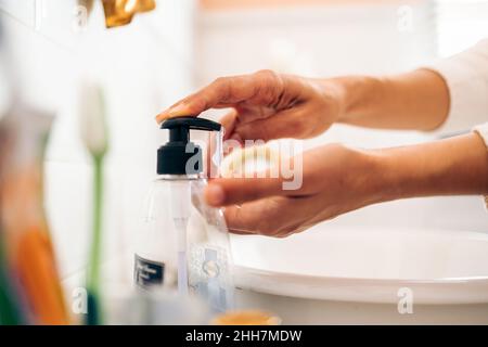 Woman using soap dispenser indoors, closeup view Stock Photo