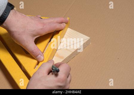 Carpenter using a pencil and old square marking a diagonal line on a wood board Stock Photo