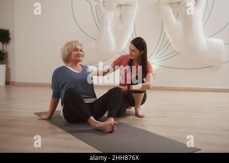 Professional trainer teaching yoga to senior woman Stock Photo
