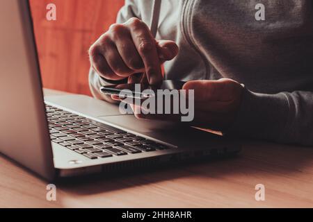 Freelancer is using mobile smart phone and laptop computer, closeup of hands with selective focus Stock Photo