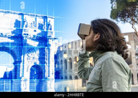 Young man in Piazza del Colosseo (Rome) looks at a virtual reconstruction with a cardboard viewer. The landscape around him changes, taking him on a j Stock Photo
